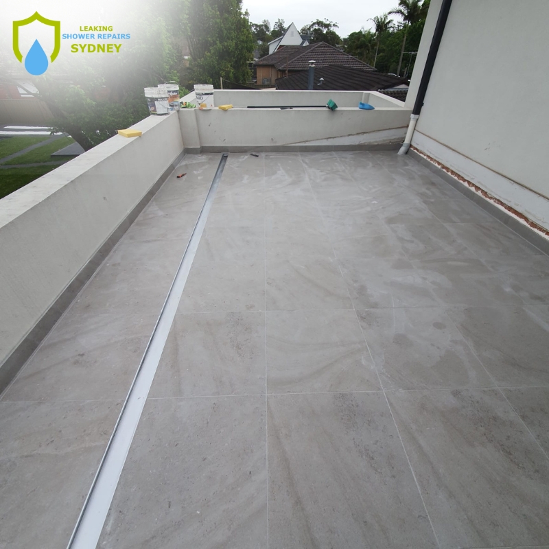 A roof featuring a distinct white line, indicative of a leaking balcony repair process.