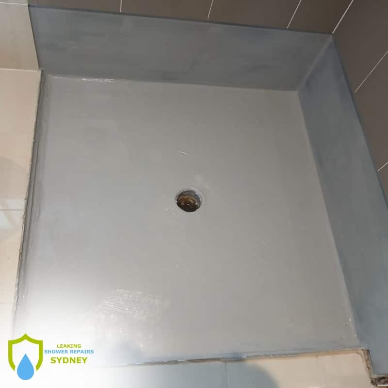Shower with a white-gray painted floor and drain, showcasing the need for Waterproofing Services in Oxley Park to ensure long-lasting durability and protection.