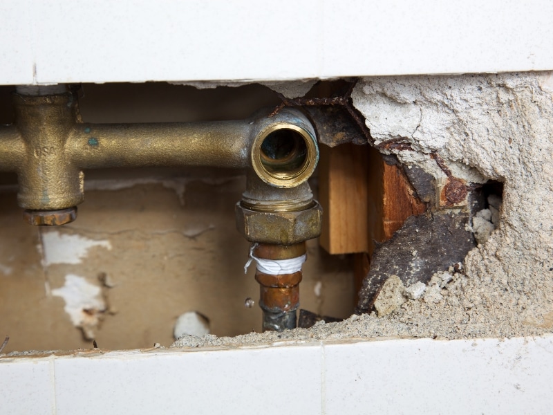 Close-up of exposed plumbing with white tape, suggesting DIY shower leak repairs in an Australian home.