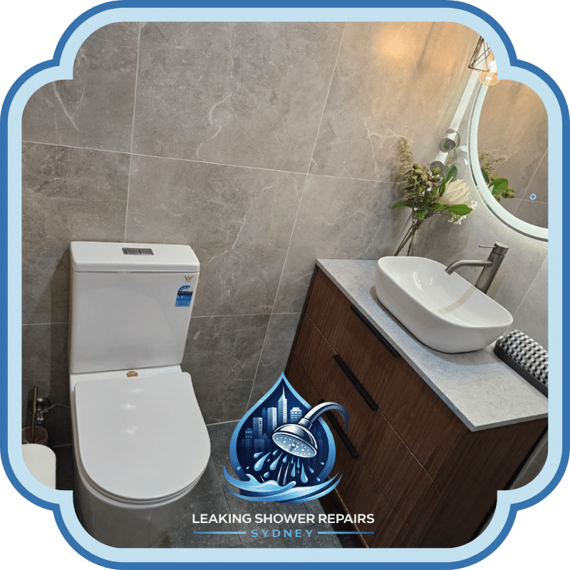 Bathroom Makeovers Services showing a modern bathroom with tiled walls, toilet, timber vanity, stone benchtop, round mirror and basin.